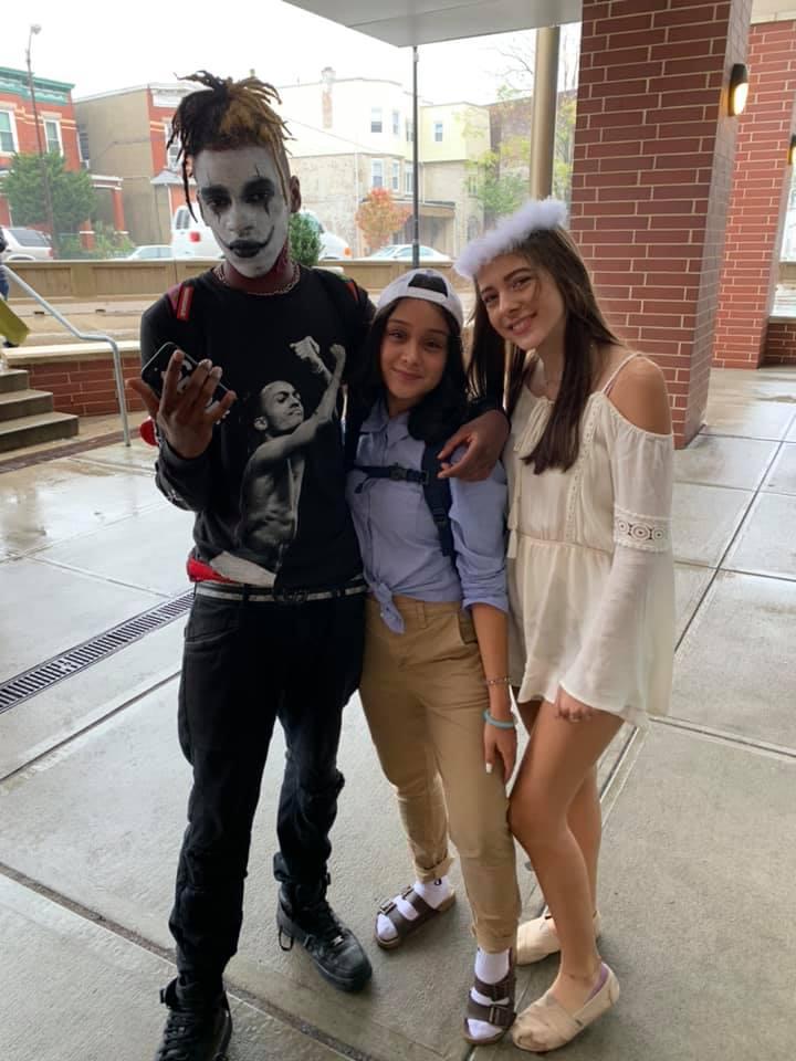 three students dressed in costume at the front entrance